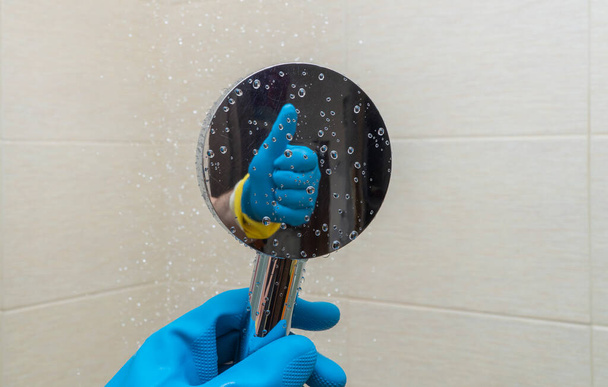 shower watering can in hands with rubber gloves. cleaning the bathroom and cleaning the shower cabin. reflection of a hand making a kind gesture. concept of good and high-quality work. copy space. - Photo, Image