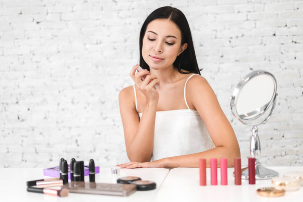 Smiling of young beautiful pretty woman clean fresh healthy white skin looking at mirror.girl holding bottle of perfume and smelling aroma at home.spa and beauty concept - Photo, Image