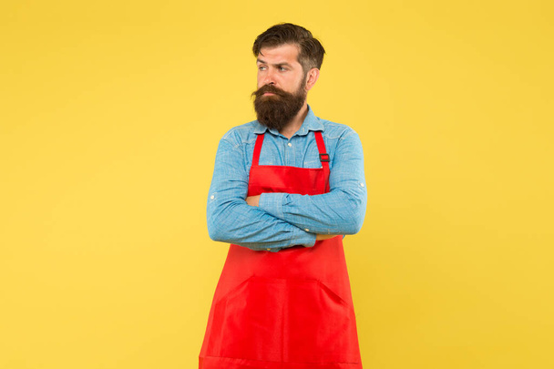 Professional cookery. his new business. guy in shop assistant uniform. serious man with red apron on yellow background. Confident expression. Handsome male barista is working. mature bartender - 写真・画像