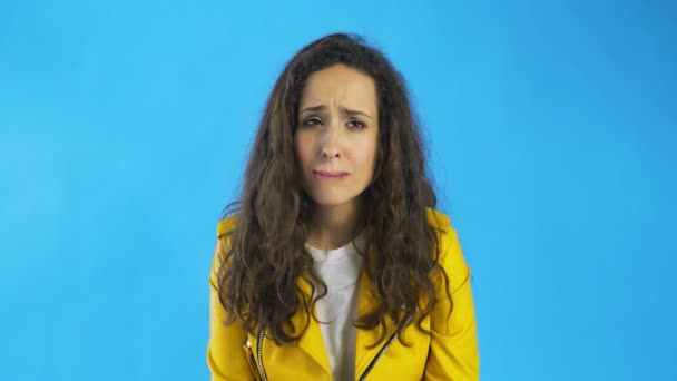Disappointed and a very sad young woman almost crying in Studio with blue Background. - Footage, Video