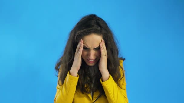 Gyönyörű lány szenved a migrén álló kék háttér, lassított felvétel - Felvétel, videó