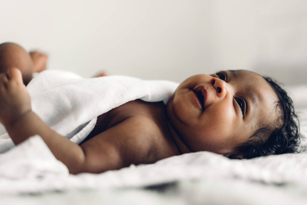 Beyaz bir yatak odasında Camara 'ya bakan sevimli, sevimli, küçük Afrikalı Amerikalı bebeğin portresi. - Fotoğraf, Görsel