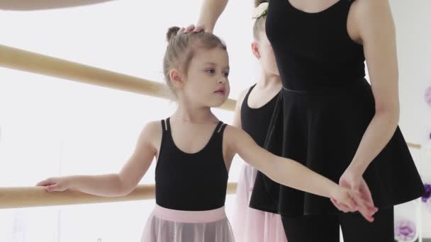 Eine Frau und ein Mädchen in einer Ballettschule. Die erwachsene Ballerina übt mit den kleinen Mädchen und trainiert das klassische russische Ballett - Filmmaterial, Video