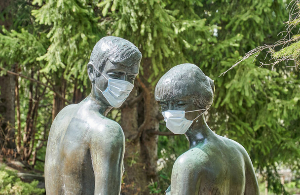 Estatua de un hombre y una mujer con máscara quirúrgica protectora sobre ellos
. - Foto, imagen