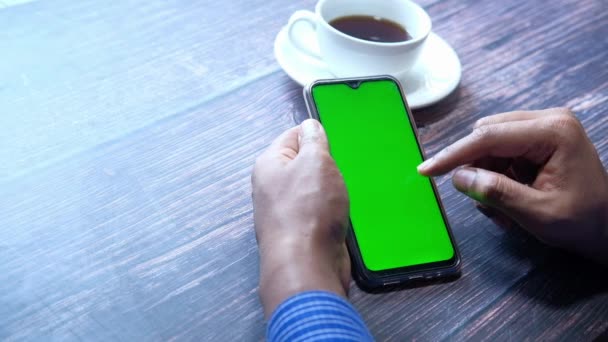 Empresario mano usando teléfono inteligente con pantalla verde en la mesa
  - Metraje, vídeo
