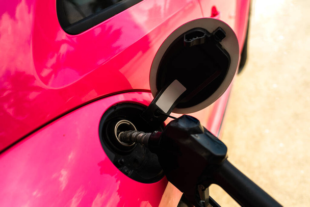 Benzinkút. Üzemanyagszivattyú. Piros rózsaszín színű üzemanyag benzin háttér. Színes benzinpumpa töltőfúvókák a benzinkútnál. - Fotó, kép