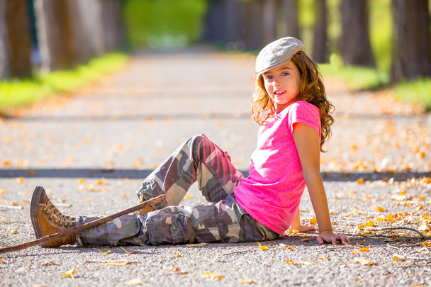 autumn kid girl with camouflage pants sitting in trees track - Фото, изображение