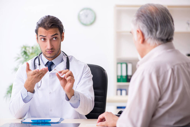 Young male doctor and old patient in antismoking concept - Foto, Bild