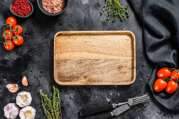 Wooden cutting board in center of Fresh raw greens, vegetables. Healthy, clean eating, vegan, dieting food concept. Black background. Top view. Copy space. - Photo, Image