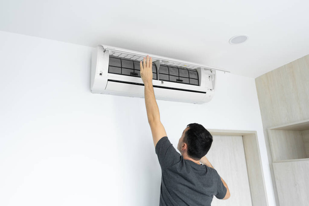 Der Mann reinigt den Filter der Hausklimaanlage vom Staub. Sehr schmutzige Klimaanlage Filter. Pflege der Klimaanlagen - Foto, Bild