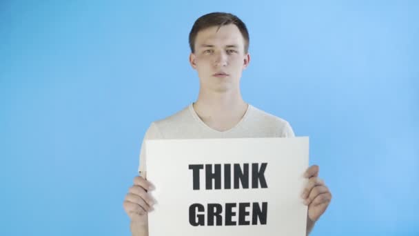 Young Man Activist With Think Green Poster on blue background - Imágenes, Vídeo
