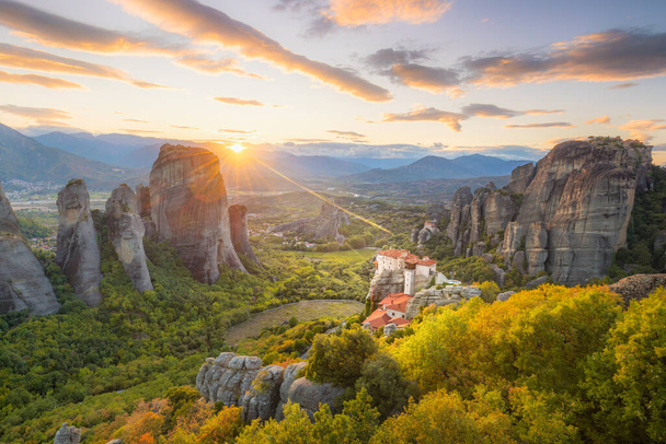 Landscape of Meteora, Greece at romantic sundown time with real sun and sunset sky. Meteora - incredible sandstone rock formations.  The Meteora area is on UNESCO World Heritage - Fotoğraf, Görsel