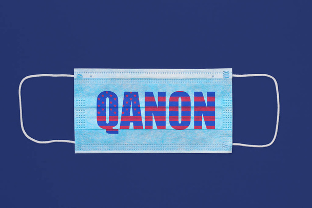 Maska chirurgiczna jako symbol chorób zakaźnych z napisem QANON w postaci flagi amerykańskiej. - Zdjęcie, obraz