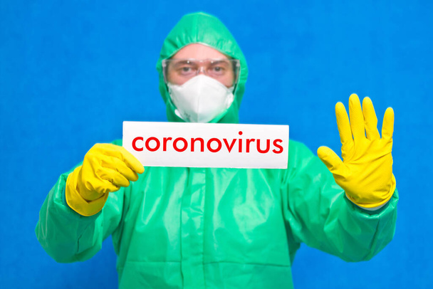 白いポスターにコロナウイルスの文字が入った医療従事者が青い背景に立っている。. - 写真・画像