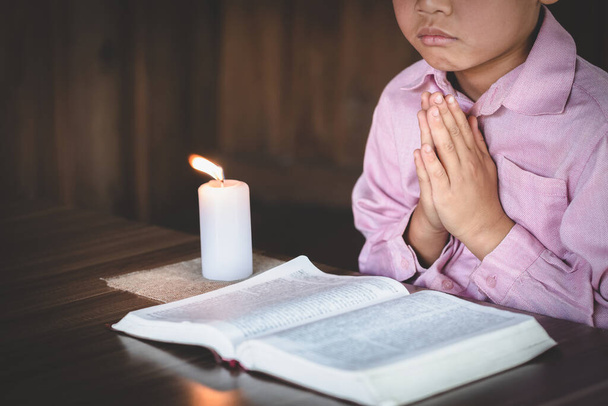 Chłopiec modlił się w pokoju i zapalił świecę. Okaż szacunek, modląc się z wiarą w religię. Namaste lub Namaskar ręce gest, pozycja modlitewna - Zdjęcie, obraz