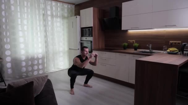 The athlete trains hard at home, performing jumps from the squat - Footage, Video