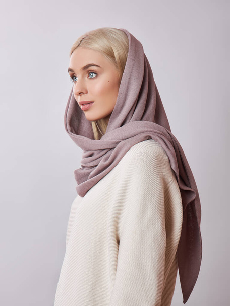 European Muslim woman with a blonde hair in a headscarf shawl dressed on her head. Beautiful girl in sweater with soft skin, natural cosmetics - Foto, imagen