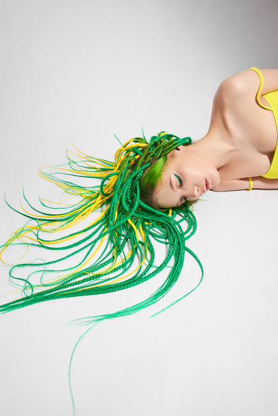 Portré egy nő kreatívan színes haj zöld és sárga színű. Színes fényes raszta, gyönyörű modern smink - Fotó, kép
