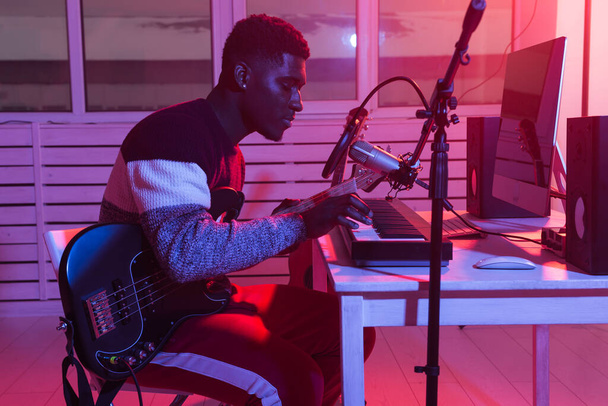 Musik und Studiokonzept erstellen - afrikanisch-amerikanischer Gitarrist nimmt Synthesizer-Track im Heimstudio auf - Foto, Bild