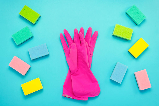 Accessories for cleaning, cleaning sponges lie on both sides and rubber gloves for cleaning in the middle on a blue background. cleaning service concept. Flat lay, Top view. - Foto, Imagem
