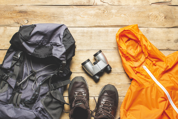 Boots for a trail, jacket, backpack, hiking gear on a wooden background. The concept of hiking, tourism, camp, mountains, forest. Banner. Flat lay, top view. - Photo, Image