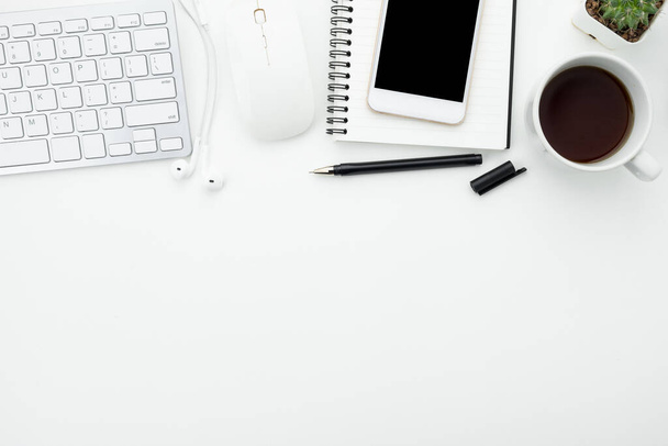 Білий офісний стіл з білим смартфоном з порожнім екраном, ноутбуком, ноутбуком та приладдям
. - Фото, зображення