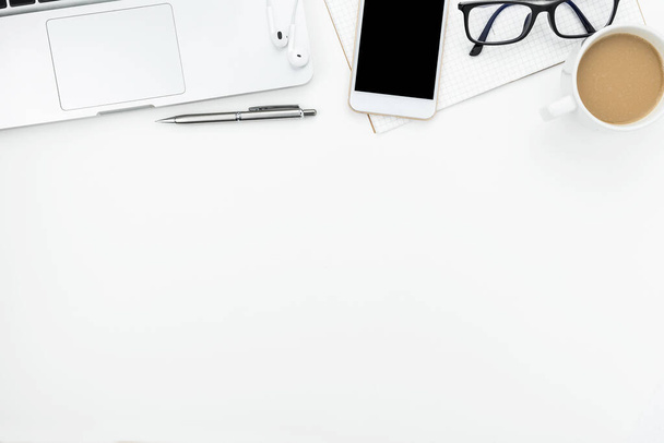 Білий офісний стіл з білим смартфоном з порожнім екраном, ноутбуком, ноутбуком та приладдям
. - Фото, зображення