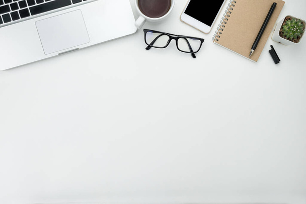 Biały stół biurowy z białym smartfonem z czystym ekranem, notebooka, laptopa i zaopatrzenia. - Zdjęcie, obraz