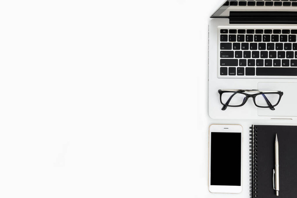 Mesa de escritorio de oficina blanca con teléfono inteligente blanco con pantalla en blanco, portátil, computadora portátil y suministros
. - Foto, Imagen