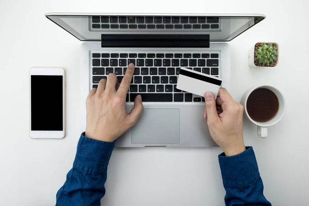 Een man gaat betalen voor de goederen op het internet met behulp van credit card en laptop computer. Online winkelen concept. - Foto, afbeelding
