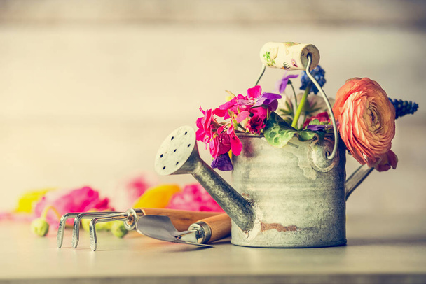 Watering can with garden flowers bunch and gardening tools on table, front view - Фото, зображення