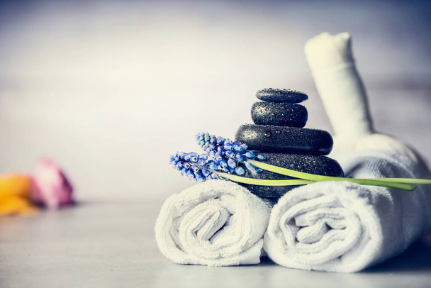 Spa massage instelling met handdoeken, hete stenen en blauwe bloemen, close-up, wellness concept, front view - Foto, afbeelding