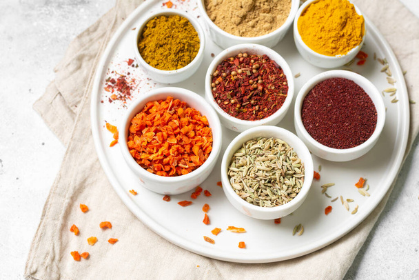 Spices and condiments in white bowls on a light gray table. Turmeric, ginger, curry, fennel and sumac in white bowls. Spices close up - Foto, Imagen
