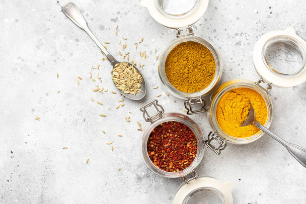 Spices and condiments in glass jars on a light gray table. Spices close-up with space for text. The view from the top - Photo, image