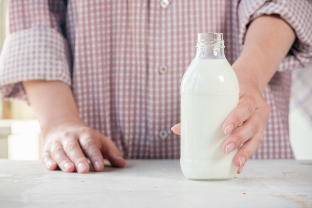 Woman is holding a fresh milk in the bottle close up. - Фото, зображення