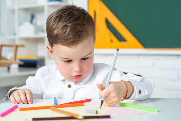 Cute little preschool kid boy in a classroom. Elementary school and education. Educational kids process. - Foto, afbeelding