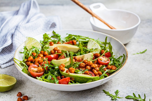 Roasted chickpea salad with avocado and tomatoes in a white bowl. Healthy vegan food concept. - Fotografie, Obrázek