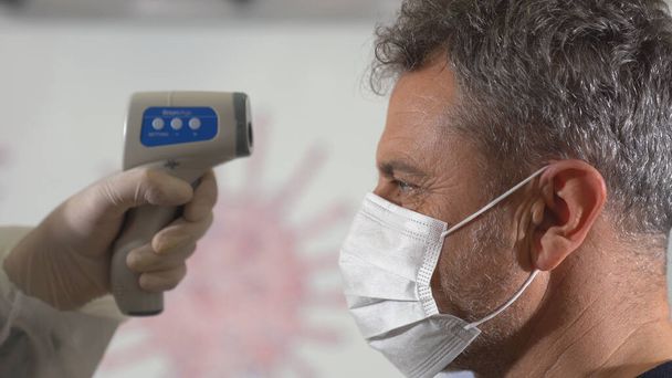 Prendre la température d'un homme avec un thermomètre pour trouver infecté par le coronavirus, Covid-19. Gros plan
. - Photo, image