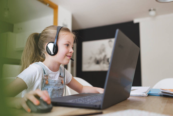 beautiful young girl with headset home studying with laptop during quarantine - Foto, Bild