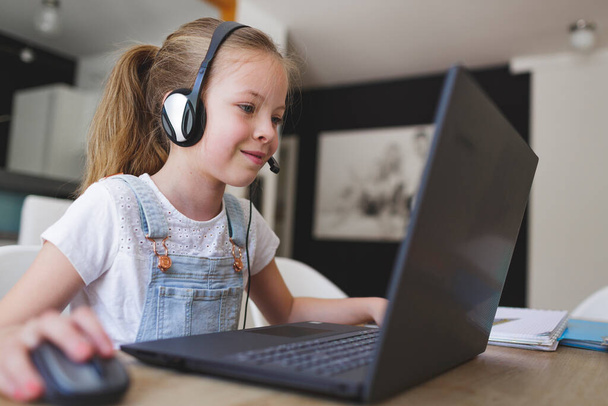 beautiful young girl with headset home studying with laptop during quarantine - Photo, image
