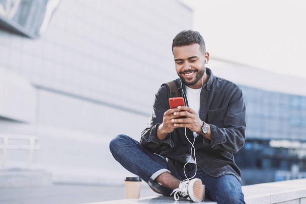 Young handsome men using smartphone in a city. Smiling student man texting on his mobile phone. Coffee break. Modern lifestyle, connection, business concept - Photo, Image