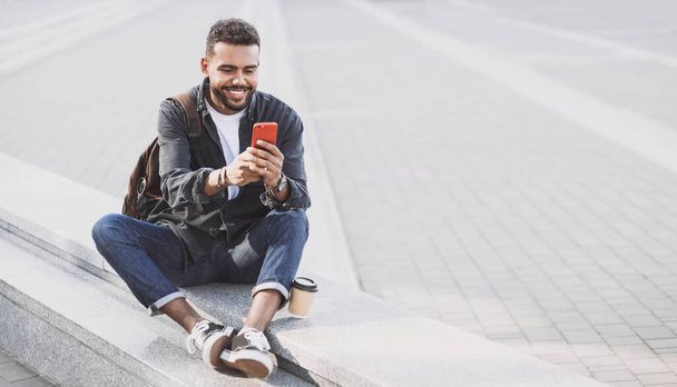 Young handsome men using smartphone in a city. Smiling student man texting on his mobile phone. Coffee break. Modern lifestyle, connection, business concept - Foto, imagen