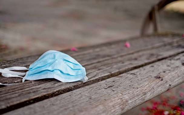 Used face mask were left on a park bench. Panoramic image with soft focus. - Photo, Image