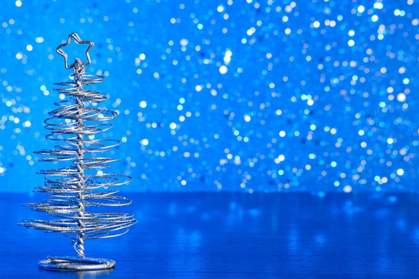 металлическая современная рождественская елка на деревянном столе на голубом фоне
 - Фото, изображение