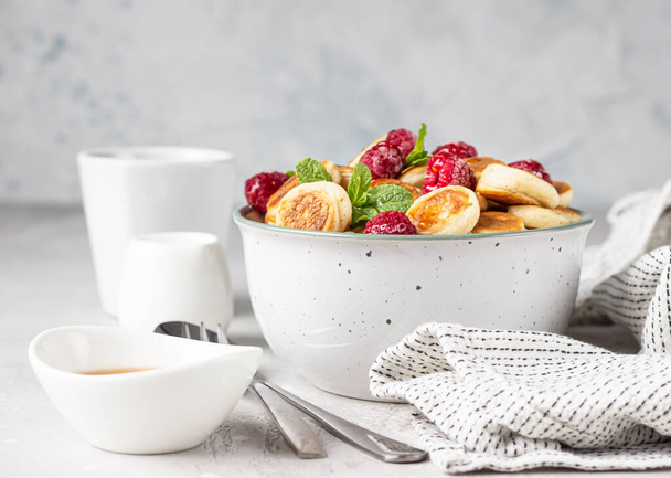 Bowl with tiny pancake cereal with raspberries, mint and jam on a light grey concrete background. Trendy food. Pancake porridge. - Zdjęcie, obraz