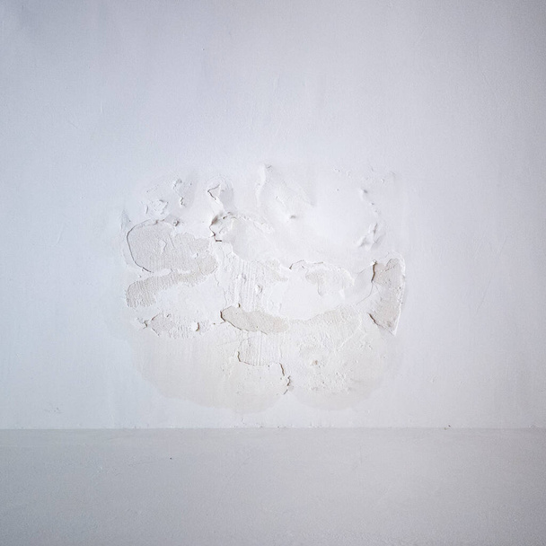 Törés a fehér falon. A vakolat leomlik a plafonról. Hosszú sor található a texturált felületen a keret teljes hosszában - Fotó, kép