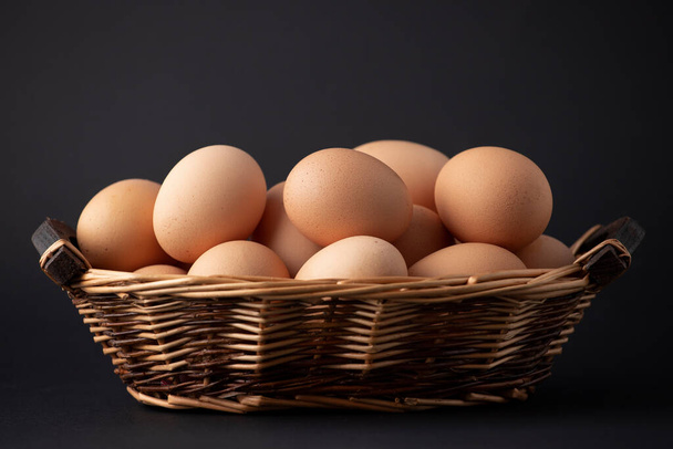 cesta de madeira com ovos em um fundo preto
 - Foto, Imagem
