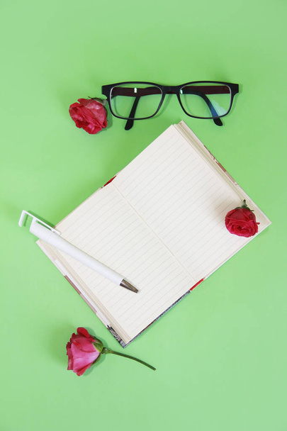 Σημειωματάριο, χαρτικά στυλό, γυαλιά και ροζ ένα τριαντάφυλλο - Φωτογραφία, εικόνα