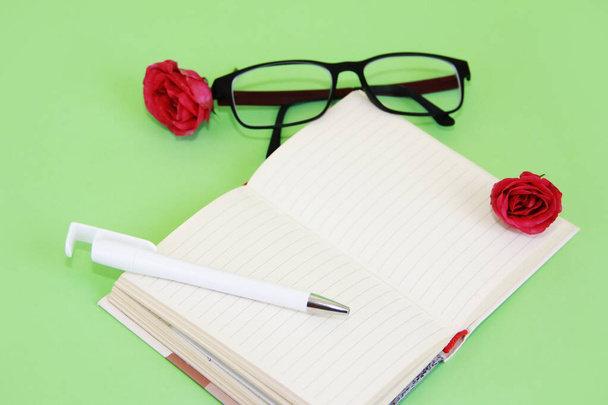Блокнот, канцелярская ручка, очки и розовый роза
 - Фото, изображение