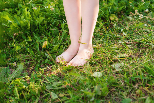 Barfuß steht ein kleines Kind auf einer grünen Wiese im Park. Kind in der Natur. - Foto, Bild
